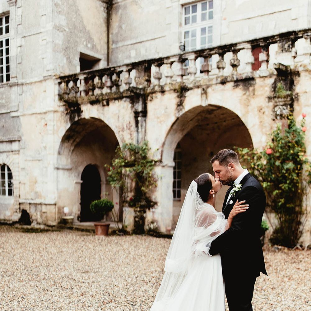 Bride & groom kiss in front of French Chateau wedding venue