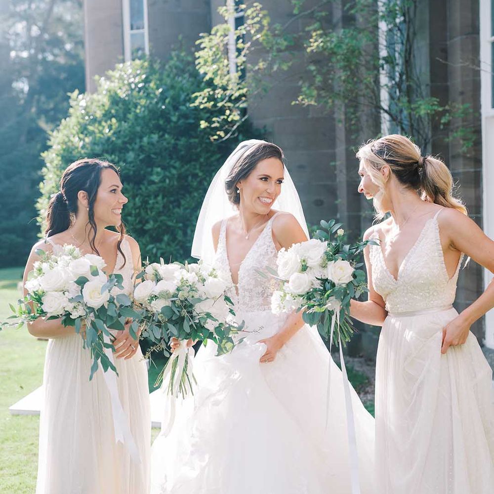 Bride and bridesmaids laughing in a Martina Liana wedding dress and needle & Thread bridesmaid dresses 