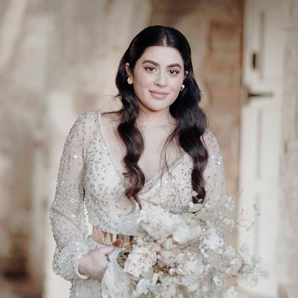 Bride with long wavy hair in a sparkly wedding dress holding a dried flower wedding bouquet 