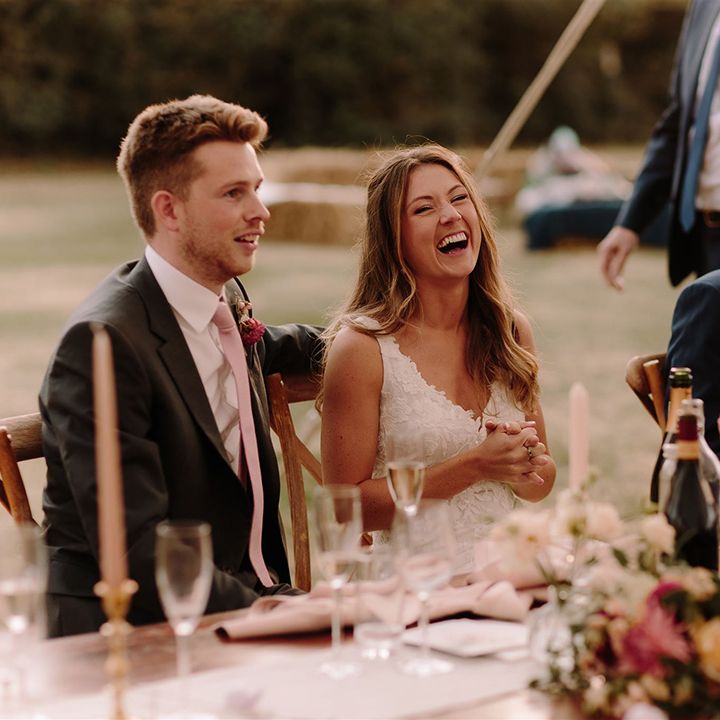 Bride and groom laugh at wedding speeches