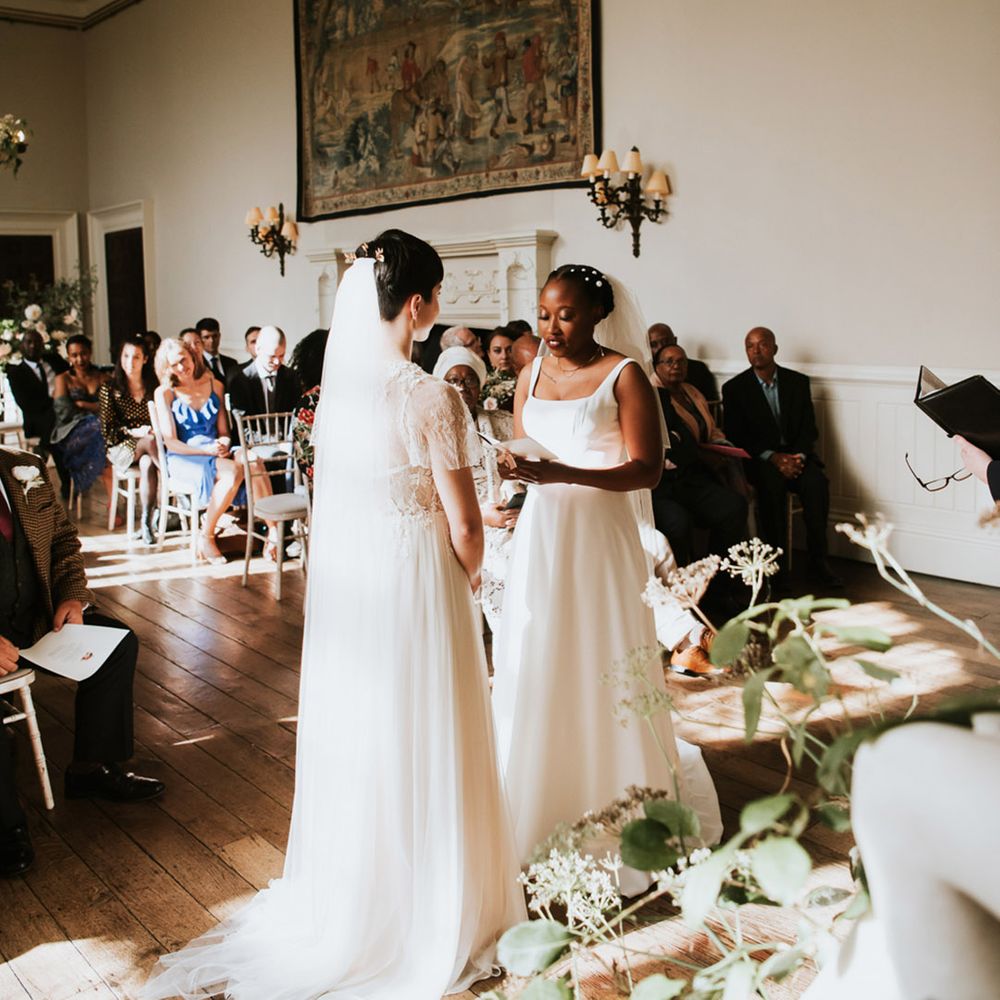 Black bride with short hair decorated with peal clips in an Essense of Australia wedding dress reading her personalised wedding vows 