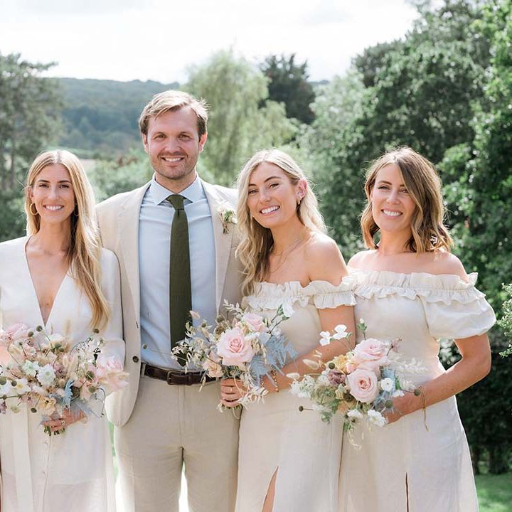 Groom with the bride wearing Bon Bride and bridesmaids in off the shoulder dresses and pastel pink and blue bouquets