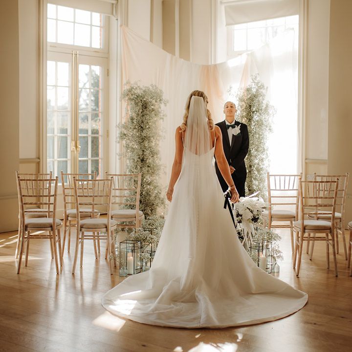 Bride in a princess wedding dress with puddle train and cathedral length wedding veil standing at the aisle at Hodsock Priory 