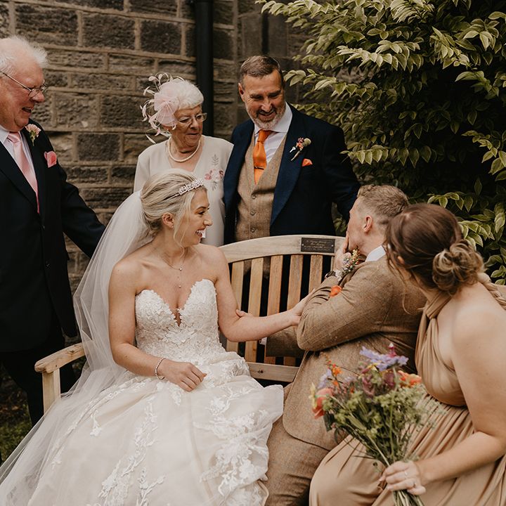 Bride and groom and other family members sit on a bench in memory of lost loved one