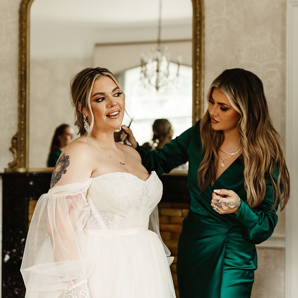 YouTube star Jamie Genevieve helps the bride with some body makeup as she wears custom strapless wedding dress with sheer sleeves