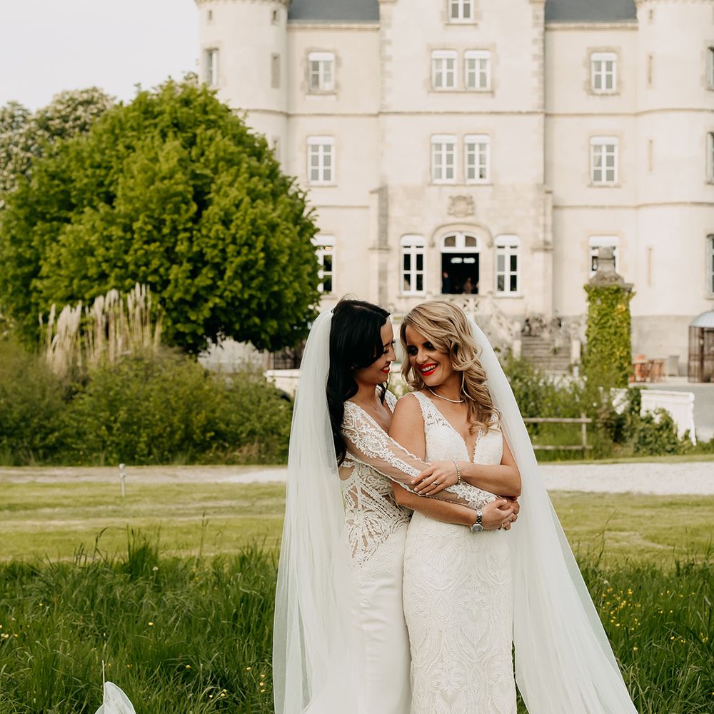Bride in long sleeve illusion lace wedding dress hugs bride in v neck lace wedding dress form behind in front of the chateau 