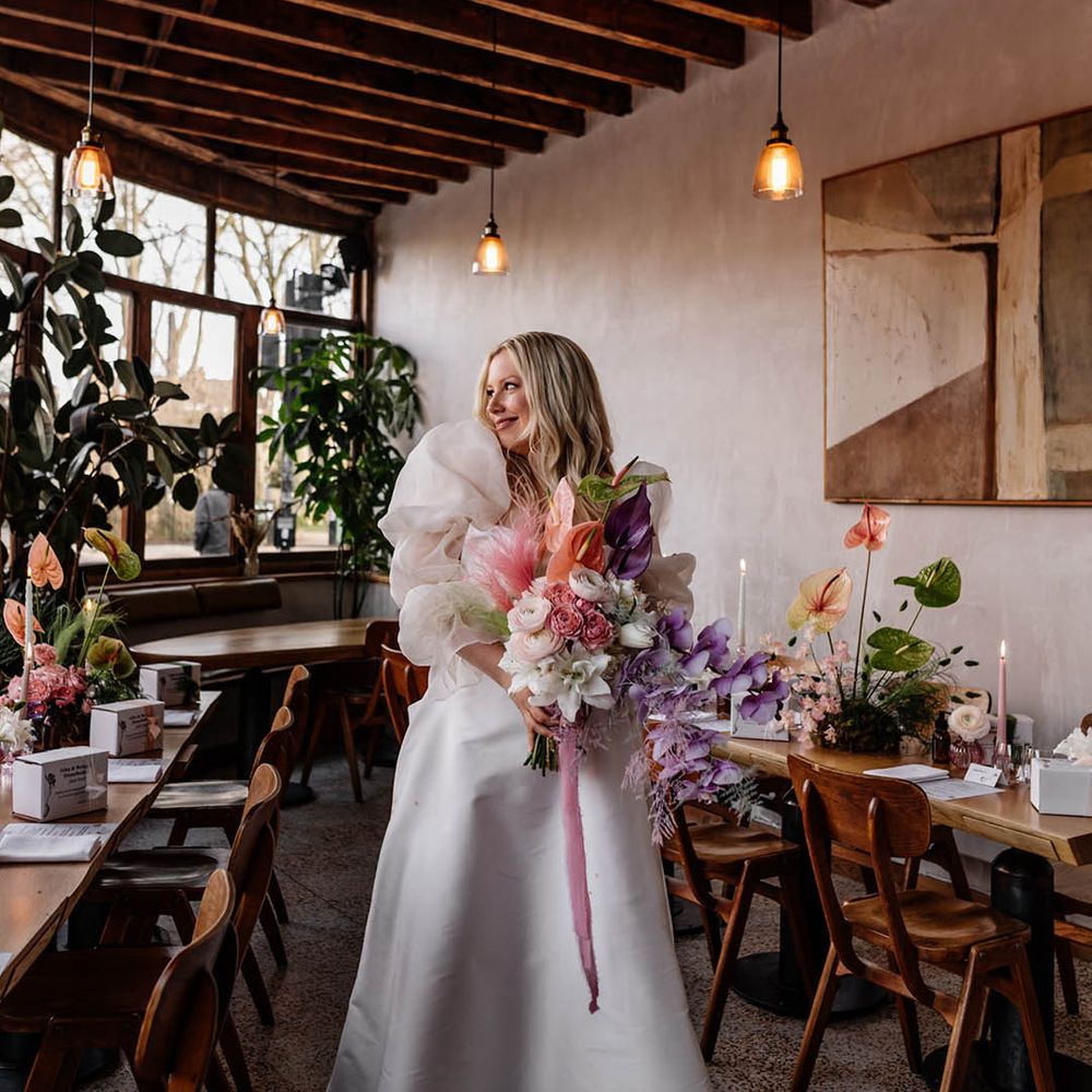 Bride in a JESUS PEIRO wedding dress with voluminous sleeves holding a pastel pink, lilac and white wedding bouquet with orchids, anthuriums and astilbe 