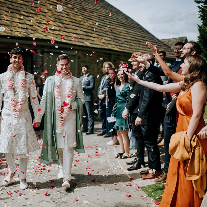 Grooms walk through colourful petal confetti exit after wedding ceremony 