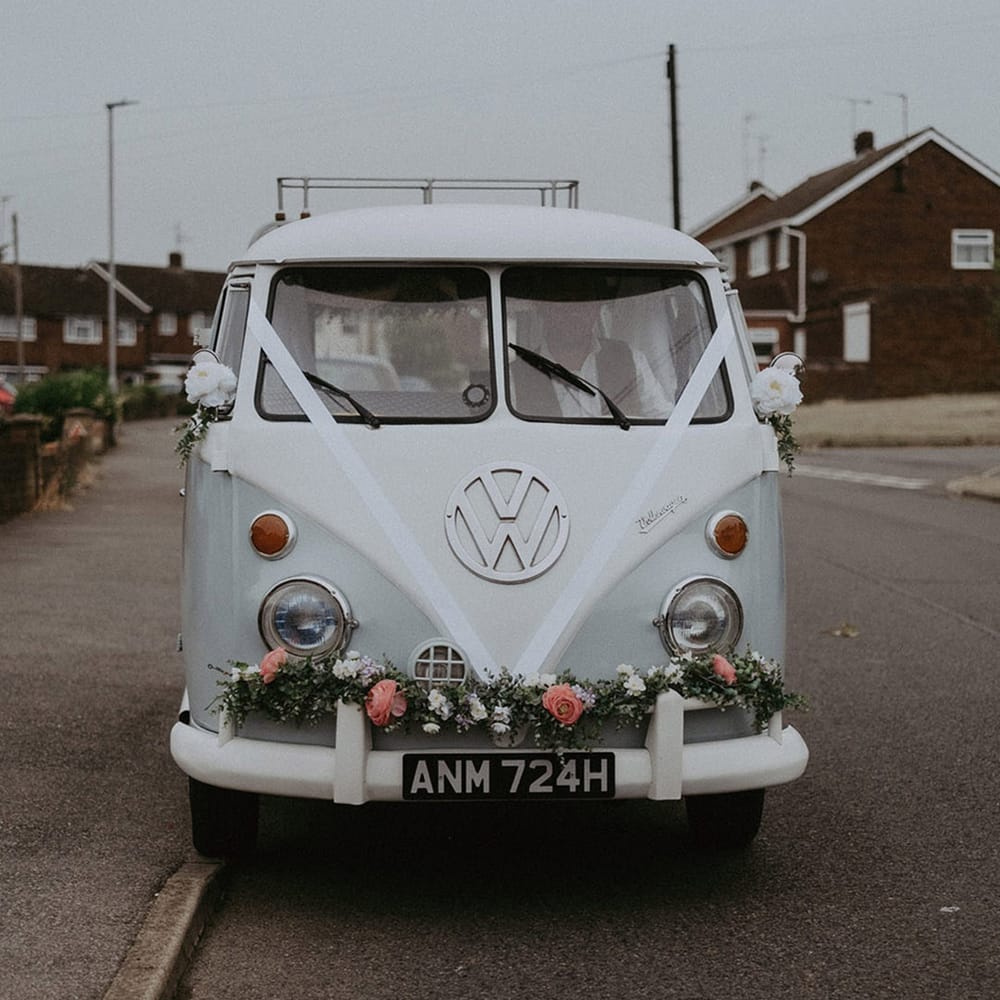 VW camper van wedding car transportation decorated with white ribbon and pink flower decor 