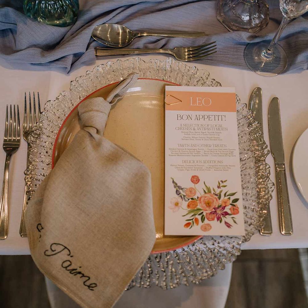 Classic wedding tablescape at Braxted Park wedding venue with white wedding tablecloth, cornflower blue wedding table runner, cream embroidered wedding napkin and botanical luxe wedding menu 
