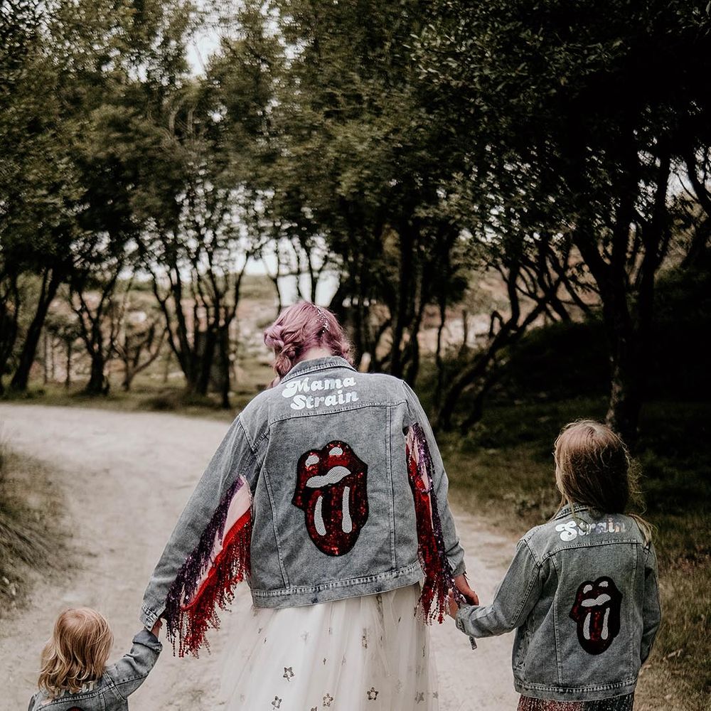 Bride in light blue wash bridal denim jacket with sequin Rolling Stones logo with sparkly tassels matching her two children 