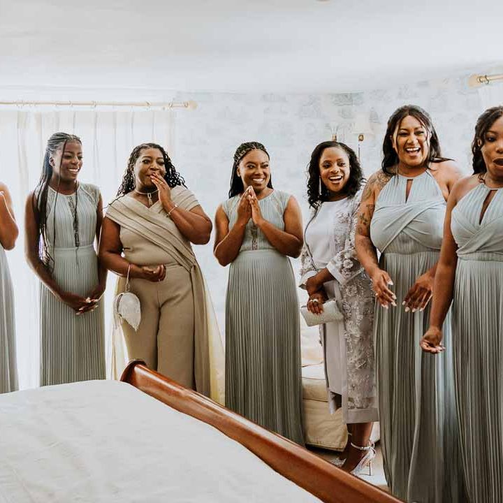 Bridesmaids in mismatched baby blue bridesmaid dresses doing first look with bride wearing V back lace and mesh wedding dress with silver hair accessories 