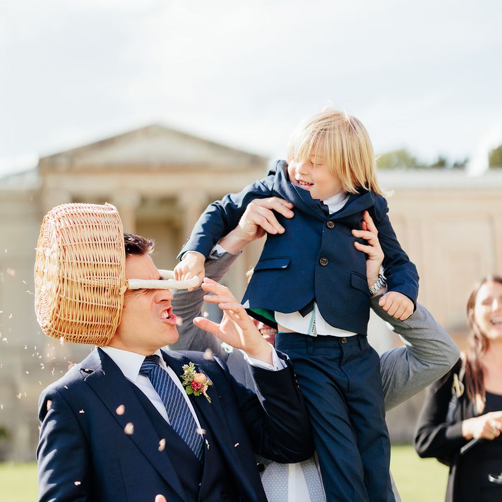 Page boy tips wicker basket full of petal confetti over the groom 
