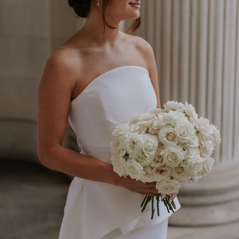 Bride in Roland Mouret wedding dress holding an all white wedding bouquet 