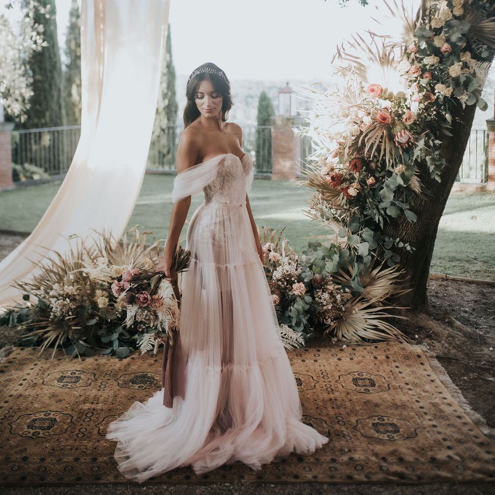 Bride in blush tulle wedding dress with off the shoulder sleeve detail 