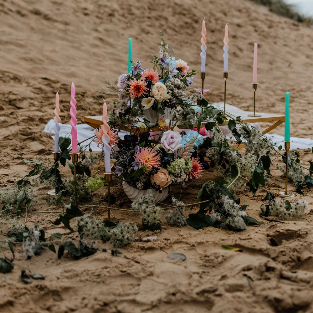 Pastel coloured wedding flowers and candles at intimate beach elopement picnic table 