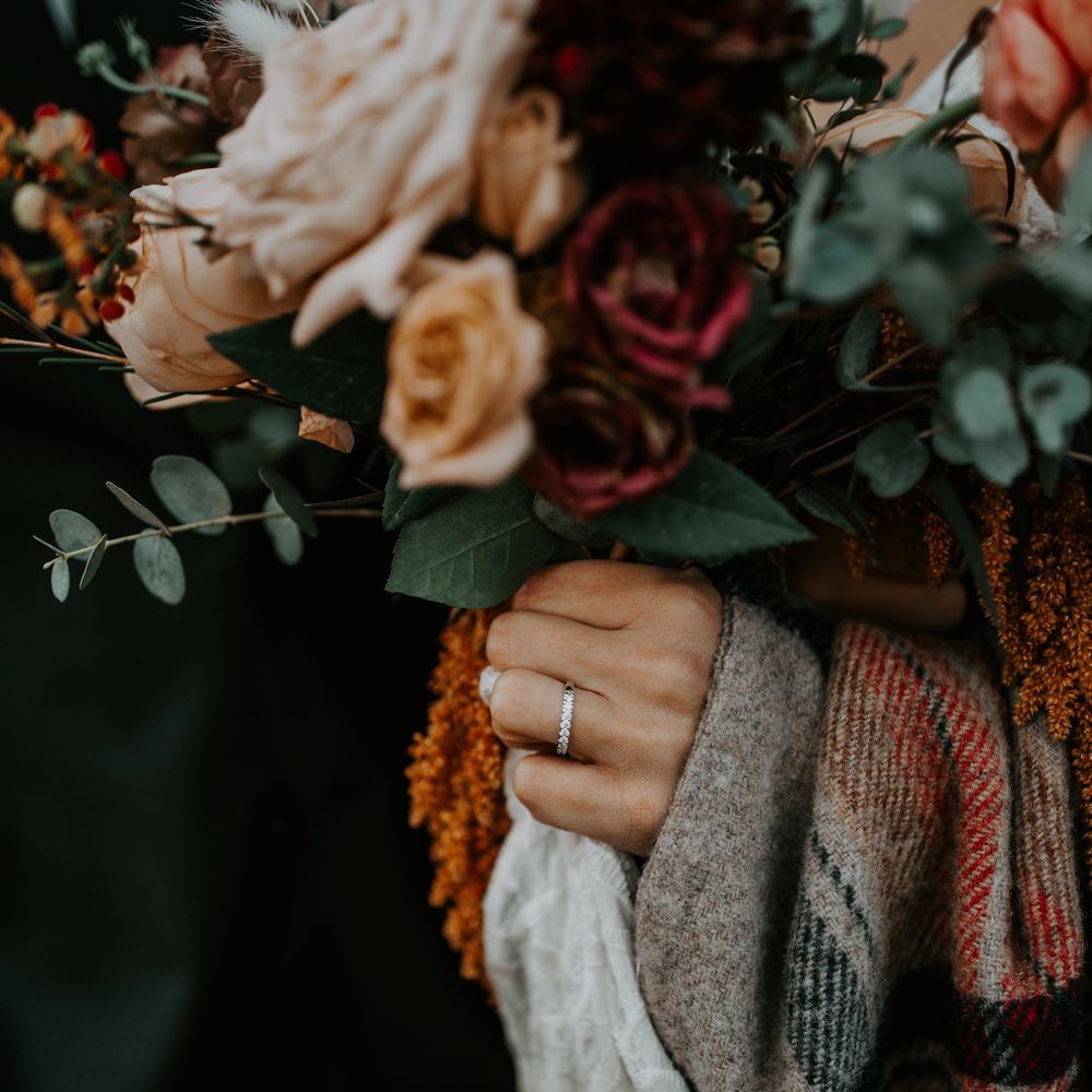 Bride holds Autumnal bouquet with dark colouring