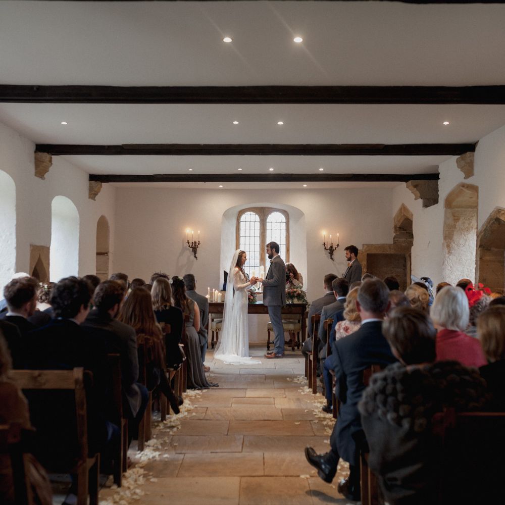 Bride and groom standing at alter with a view of the guests at Brympton House