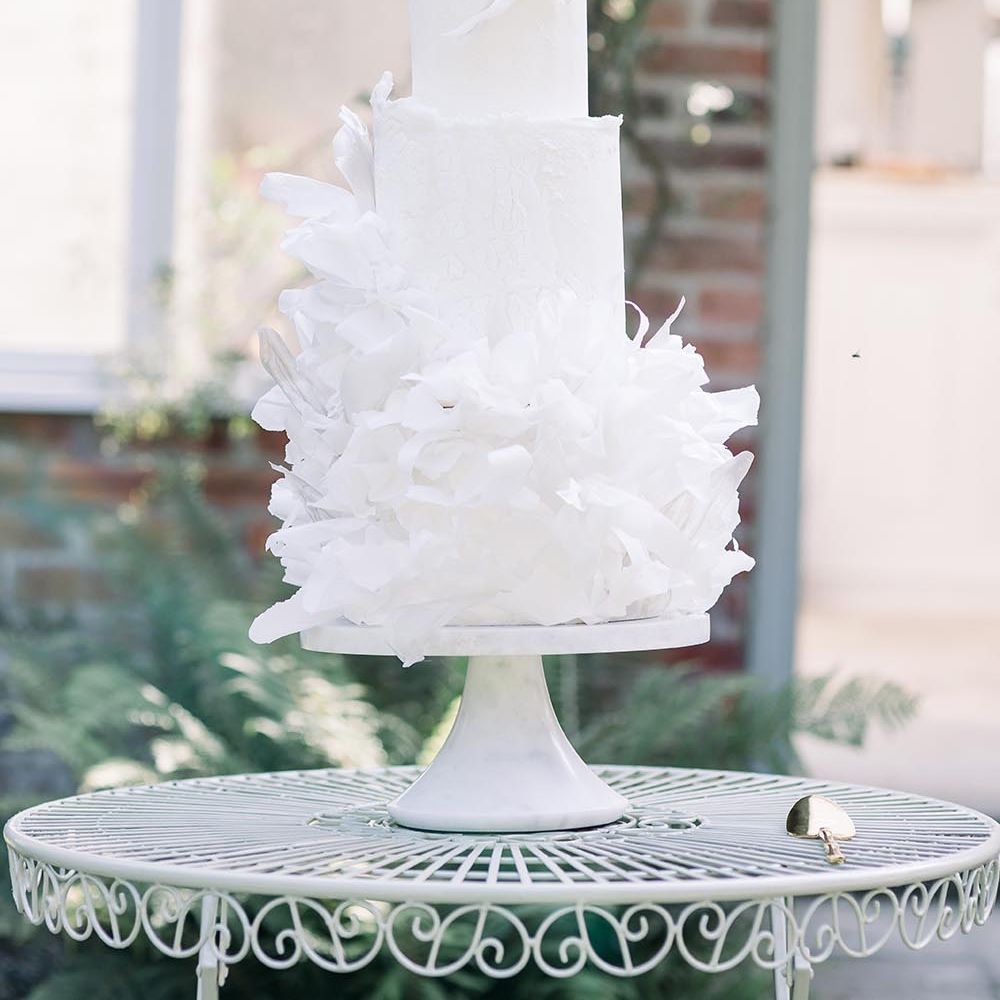 Tall white wedding cake with ruffle design by Where The Ribbon Ends