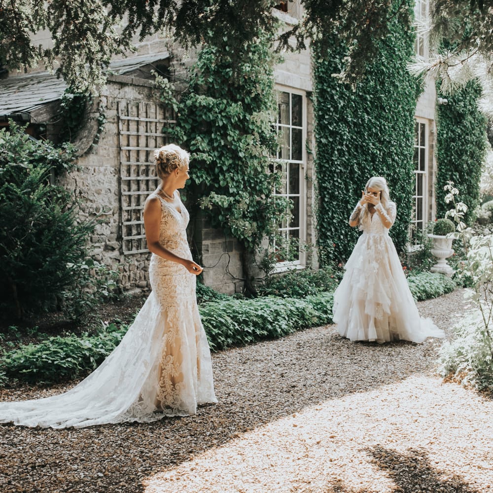 Two brides engage in a 'first look' before their wedding ceremony. 