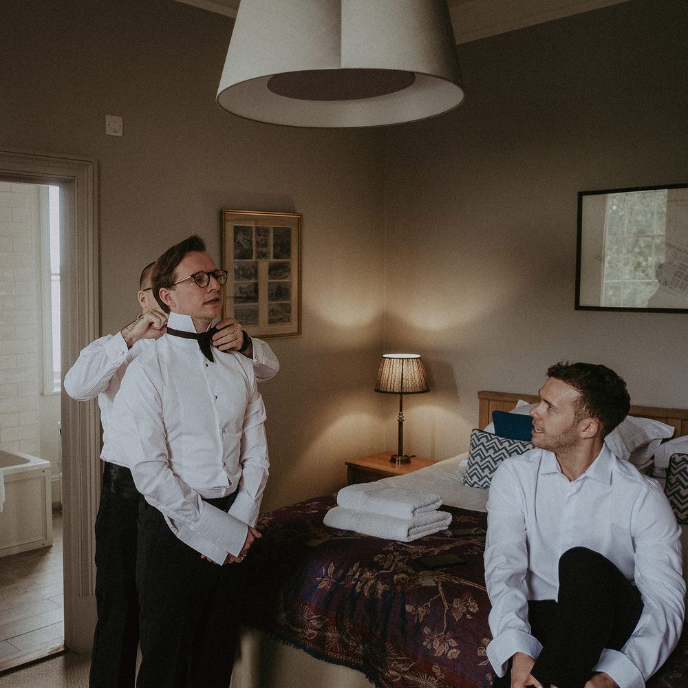Groom gets ready on the morning of his wedding day in black tie