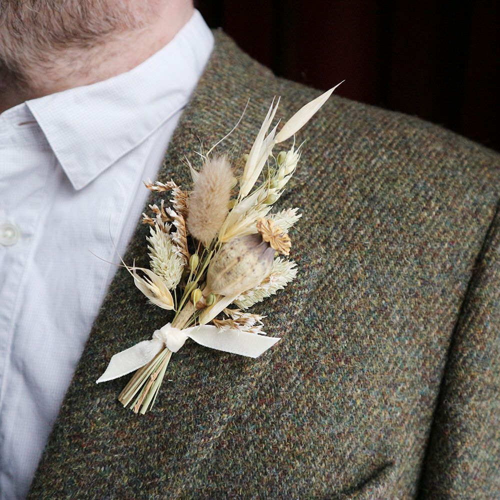 Pale dried flower buttonhole on tweed lapel