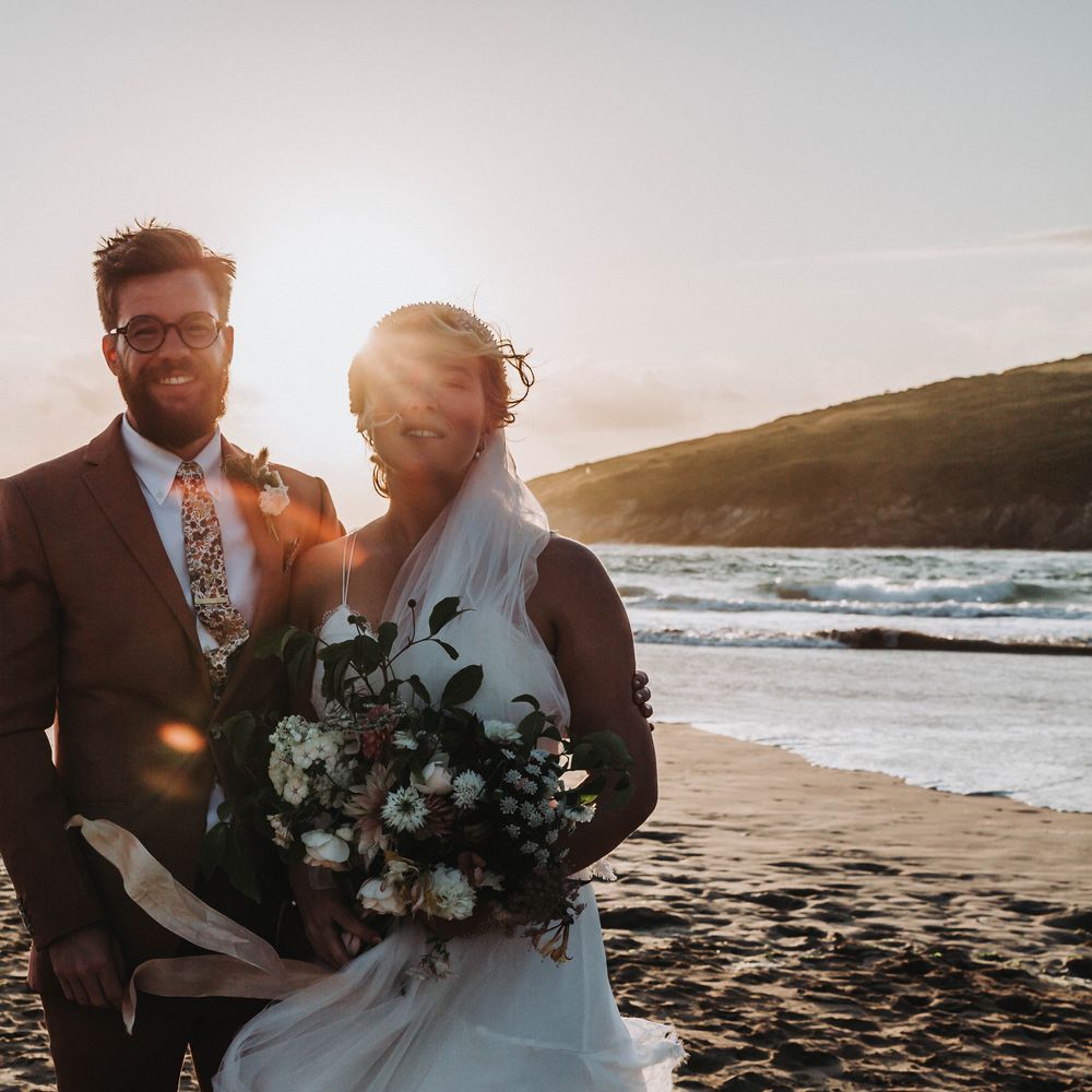 Bride & groom stand on the beach with one another on their wedding day for golden hour portraits