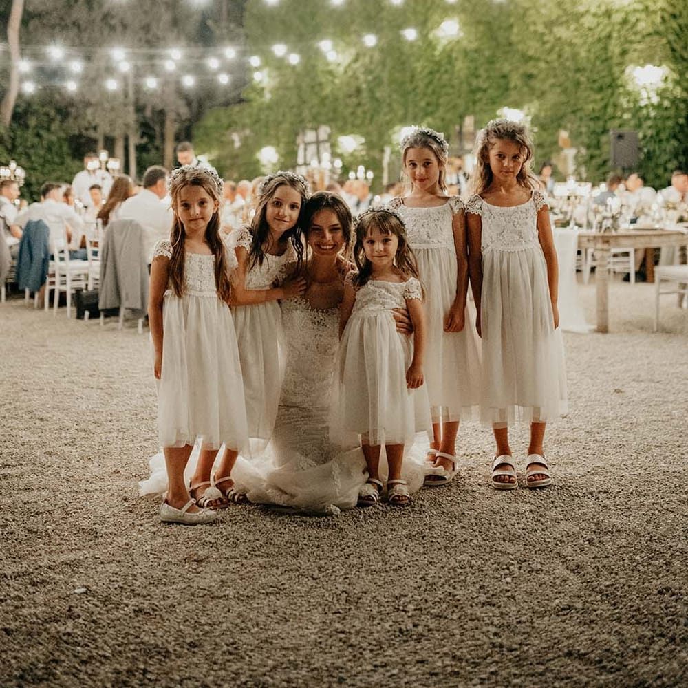 Bride sits with her flower girls outdoors during wedding reception in Italy | Royal Studio