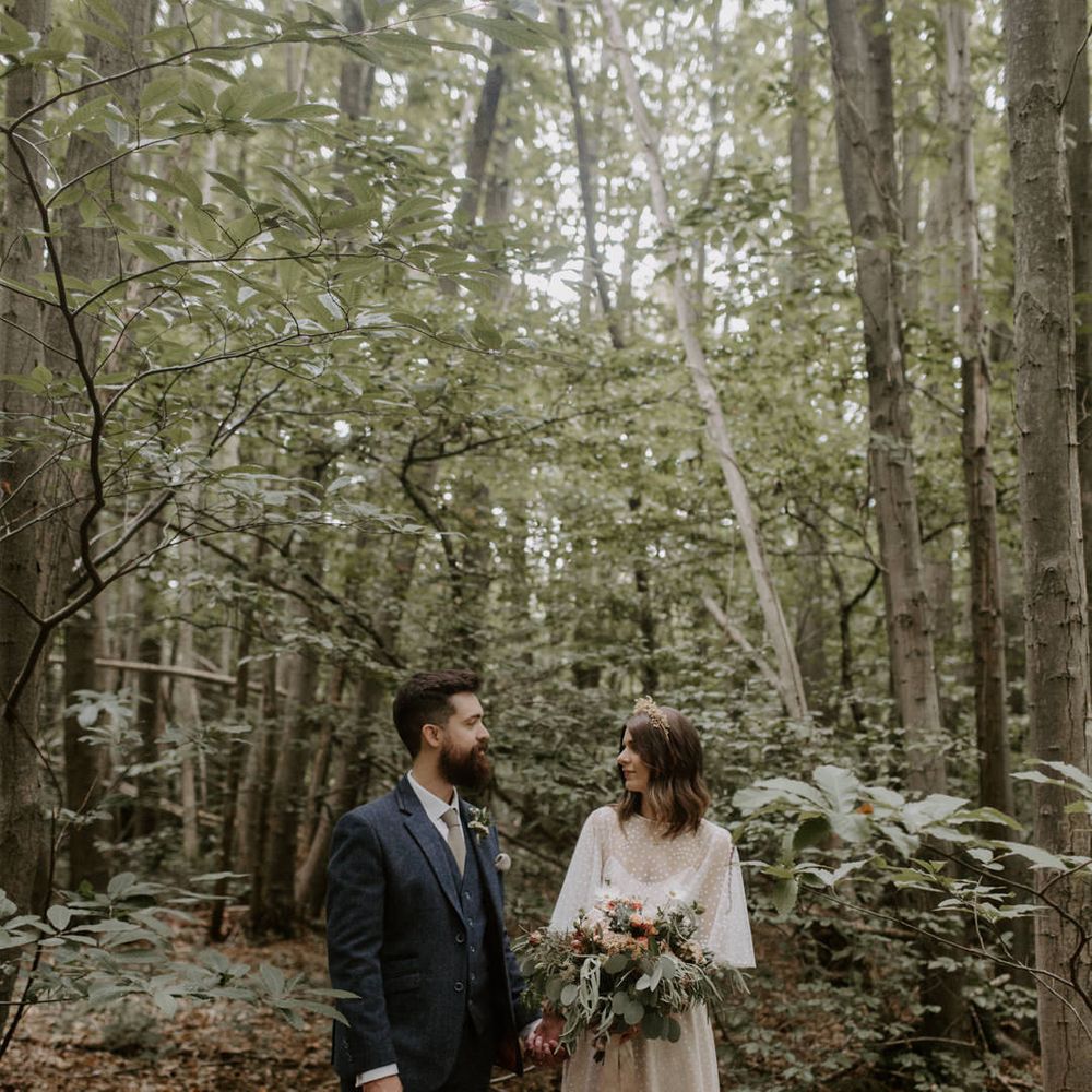 Bride & groom look lovingly at one another as bride wears E&W Couture wedding gown