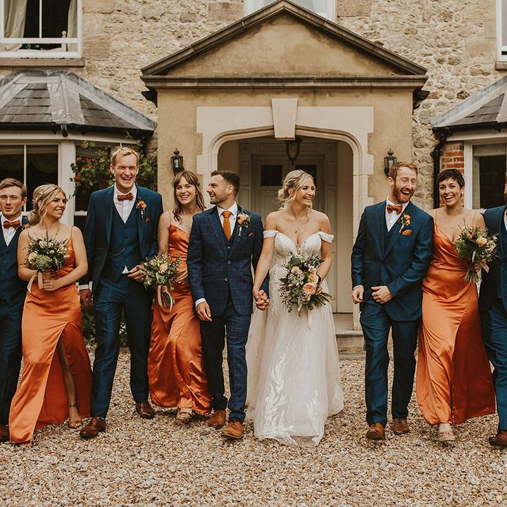 Bridesmaids in orange dresses with groomsmen in blue suits