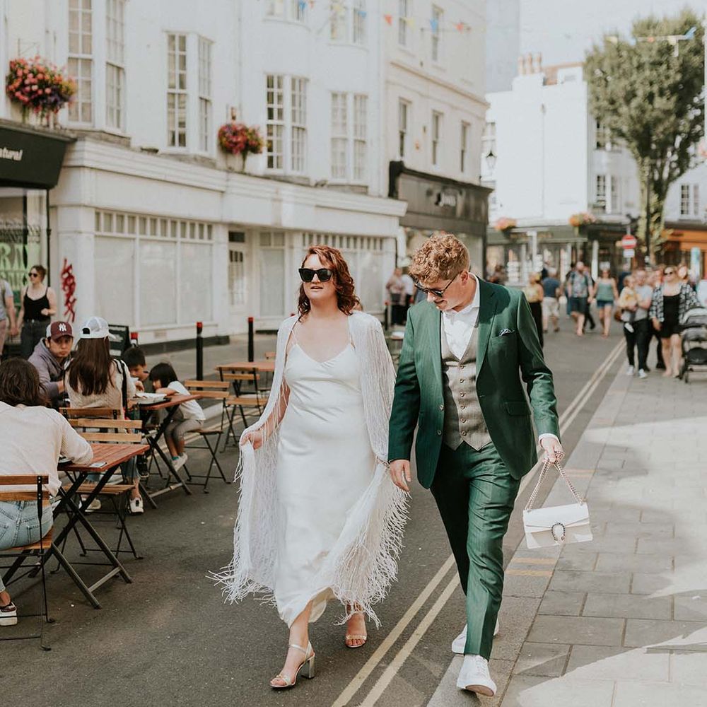 Bride & groom walk hand in hand on their wedding day through the streets of Brighton