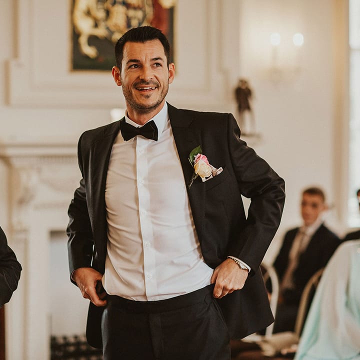 Groom wears black tie on his wedding day complete with floral buttonhole 