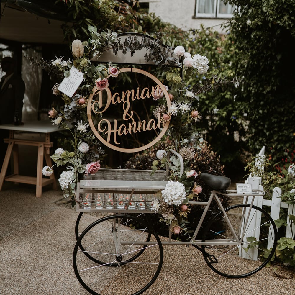 Three wheeled wedding bike complete with personalised name sign and tray filled with glasses 
