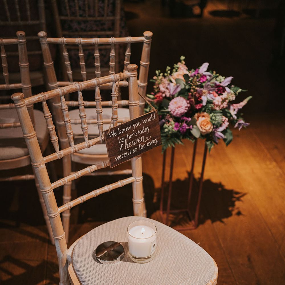 Light wooden and cream chair with a lit candle and wooden plaque for those lost