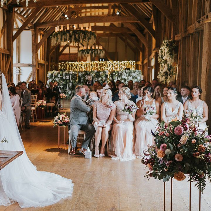 Bride and groom at the altar with bride in tulle puddle train dress at rustic wedding venue complete with hanging wisteria and fairy lights 