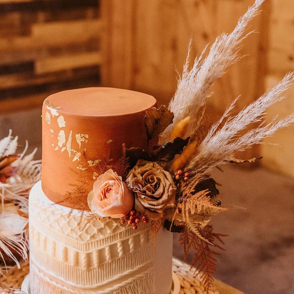 Two tier burnt orange and white wedding cake with dried flowers 