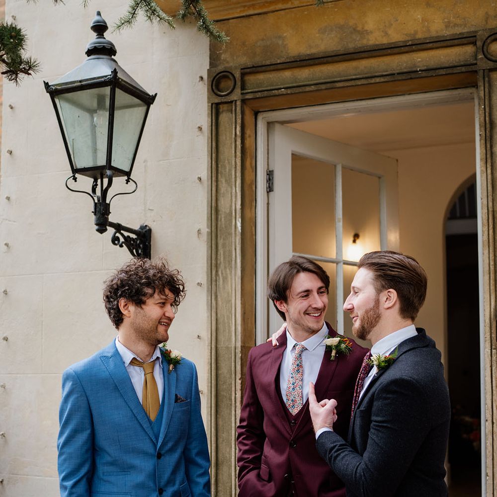 Groom speaks and catches up with guests in different colour suits after wedding ceremony 