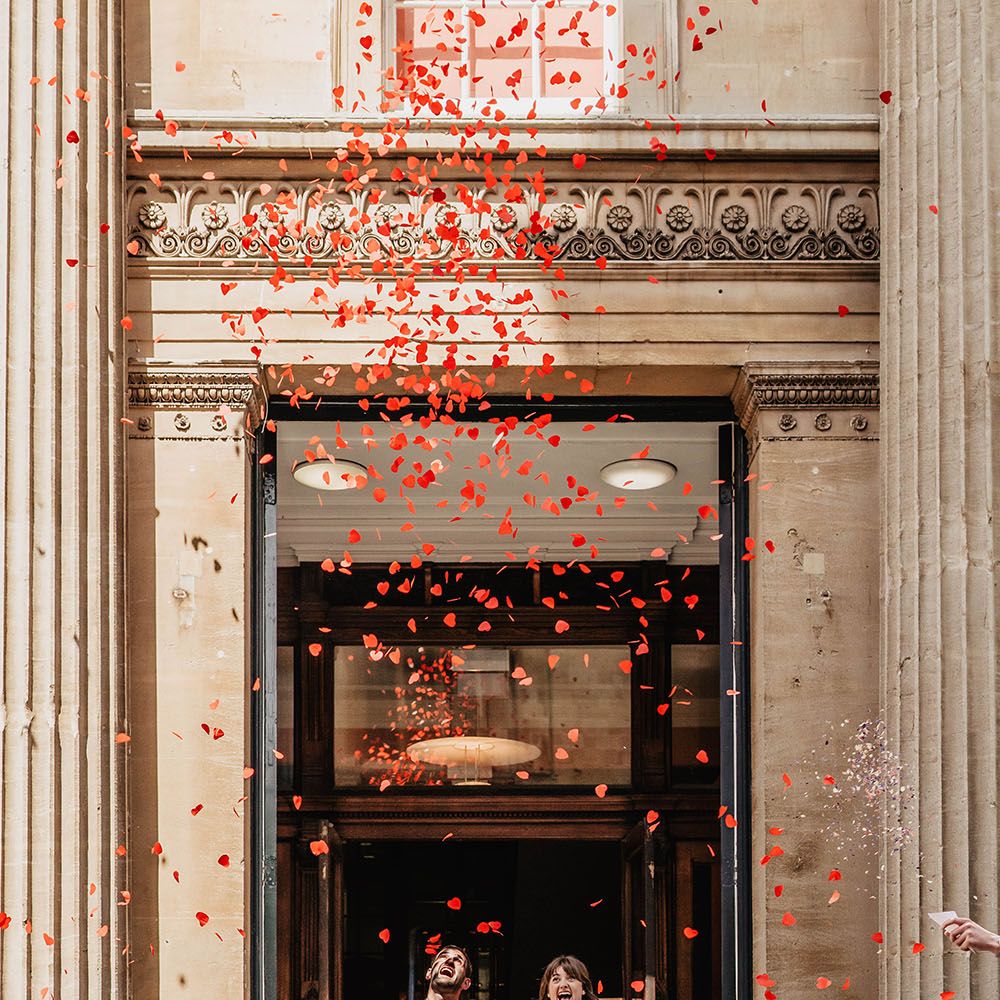 Heart shaped confetti covers bride & groom from above as they leave Bristol Register Office on their wedding day
