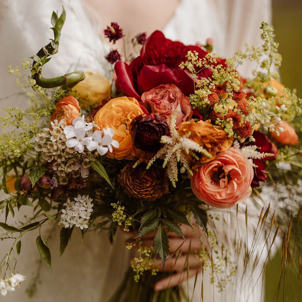Red, orange and yellow wedding bouquet with ranunculus and bamboo stems 