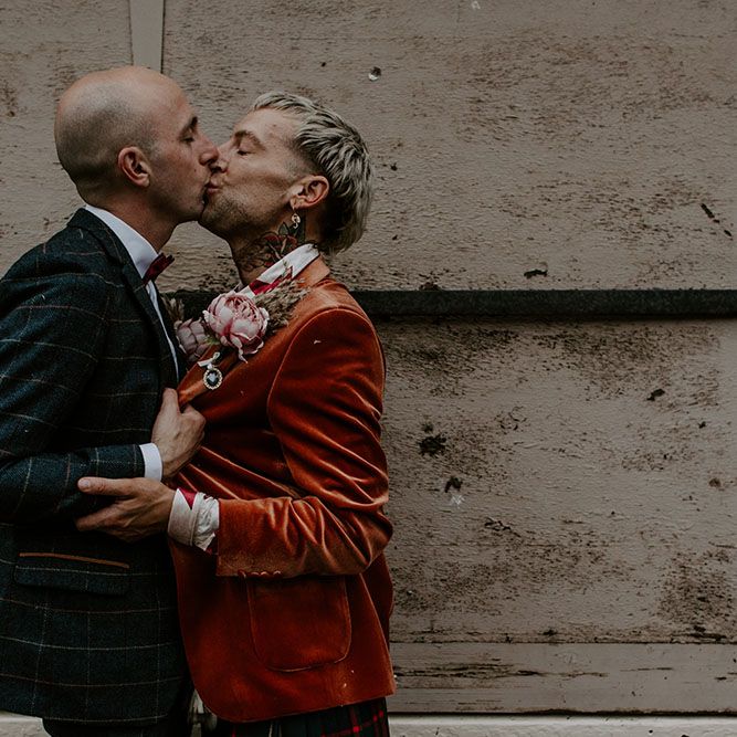 Grooms kiss outdoors on their wedding day 