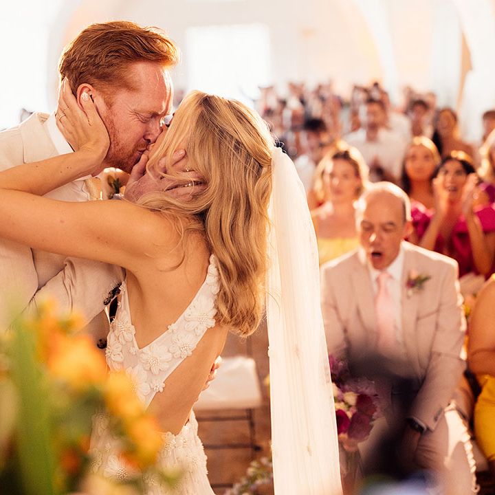 Bride and groom share their first kiss as a married couple as the wedding guests cheer 
