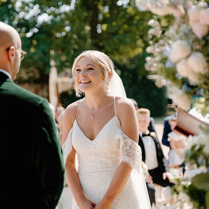Bride wears off the shoulder lace wedding dress during summer outdoor wedding ceremony
