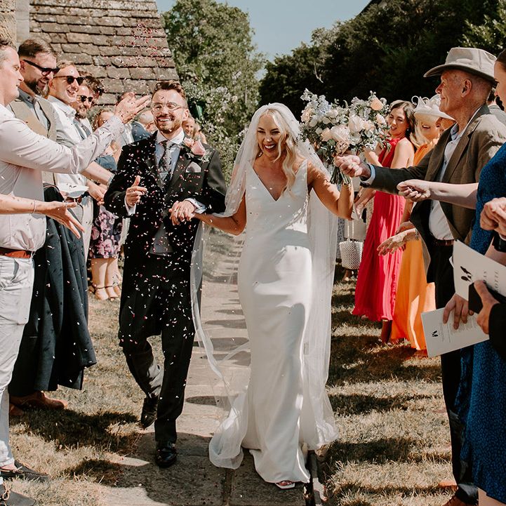The bride and groom have a confetti exit after their traditional church wedding ceremony 