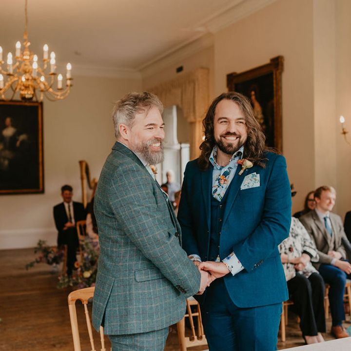 Groom wears blue three piece suit with floral shirt and matching pocket square during wedding ceremony 