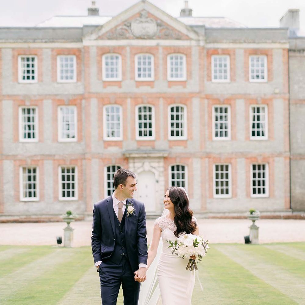 Bride and groom walking in front of their classic country house wedding venue