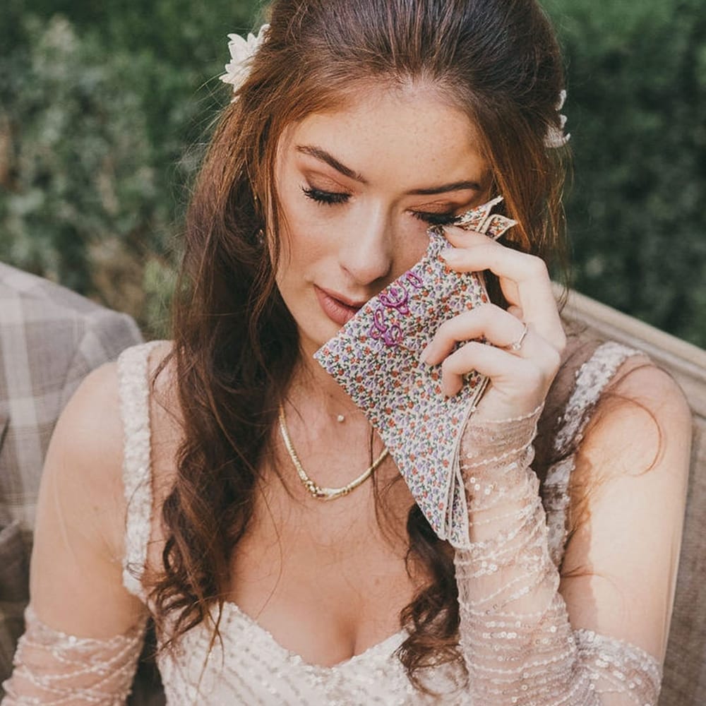 Bride wiping her tears with a personalised handkerchief wedding favour