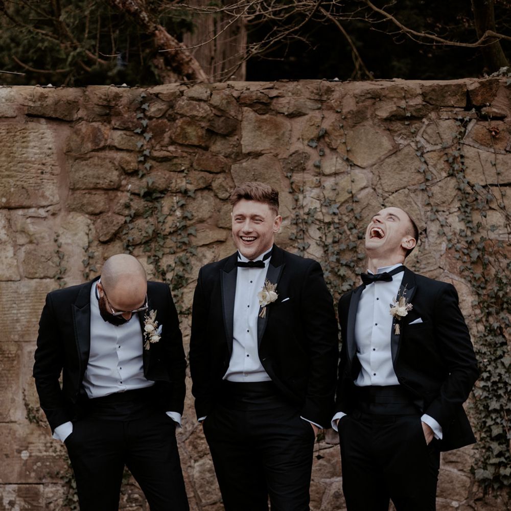 Groom and groomsmen in matching black tuxedos for the black tie wedding 