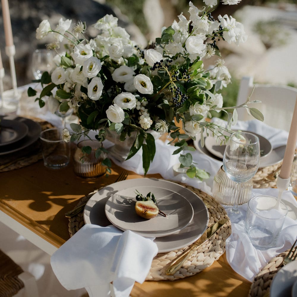 Wedding tablescape with white roses, white berries, italian ranunculous and eucalyptus, figs, ribbed jars and blush tapered candles