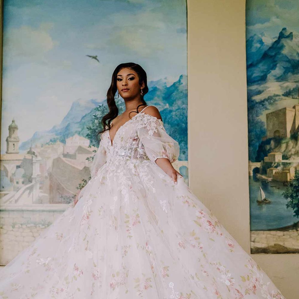 Bride standing by the hand painted murals at Braxted Park wedding venue wearing in v-neck long sleeve shoulder cut out 3d appliqué wedding dress with flecks of gold 