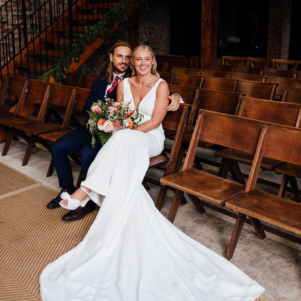 The Barn at Botley Hill in Surrey wedding with the bride and groom taking a seat together at the ceremony barn 